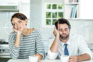 Upset couple with coffee cup sitting at table