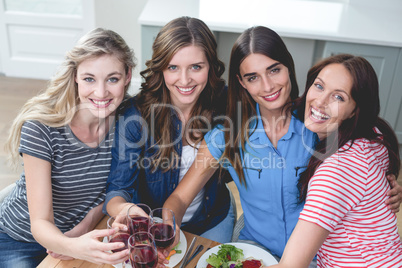 Friends holding glass of red wine while having meal