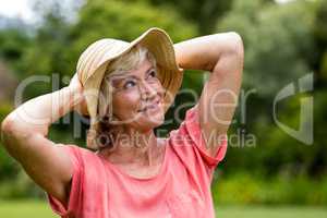Senior woman in hat standing at yard