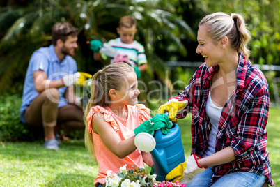 Happy mother and daughter watering flowers in yard