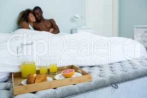 Romantic couple cuddling with breakfast tray on bed