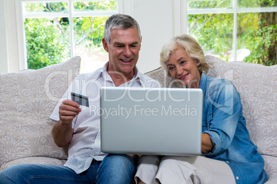Senior couple shopping online using laptop at sitting room