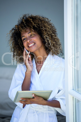 Woman talking on the phone while using the digital tablet