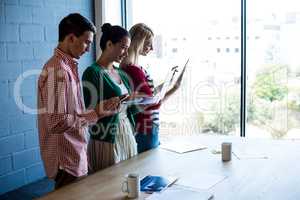 Colleagues using mobile phone, digital tablet and laptop at thei