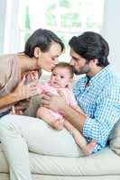 Parents kissing son while sitting on sofa