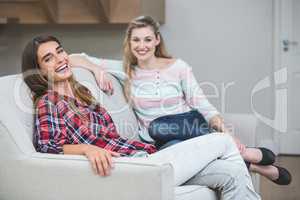 Portrait of two beautiful women sitting on sofa