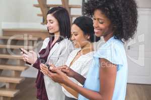 Happy female business colleagues using mobile phone