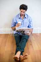 Man reading newspaper while having coffee