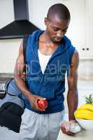 Young man carrying a gym bag, water bottle and apple