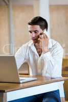 Man talking on mobile phone while using laptop