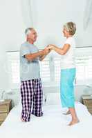 Senior couple dancing on bed at home
