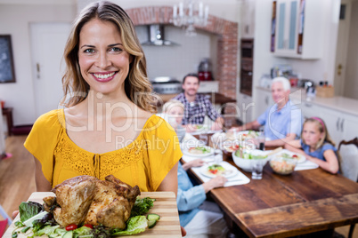 Portrait of happy woman holding a tray of roasted turkey