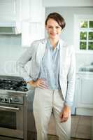 Businesswoman standing with hand on hip in kitchen