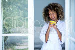 Young woman holding a cup of coffee and looking out of the windo