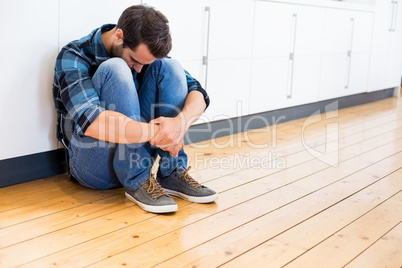 Tensed man sitting on wooden floor