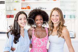Portrait of beautiful women standing with arm around in kitchen