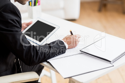 Businessman writing in a diary and using a digital tablet