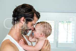 Happy father with baby boy in bedroom