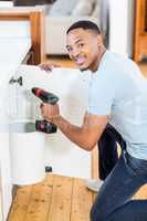 Man drilling a hole inside the cabinet