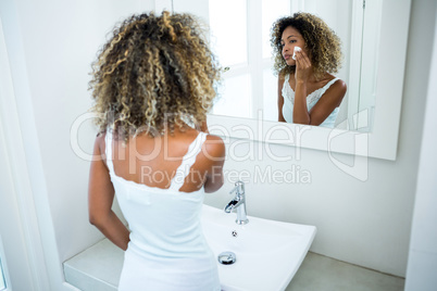 Young woman cleaning her face with sponge