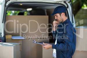 Thoughtful delivery man holding clipboard