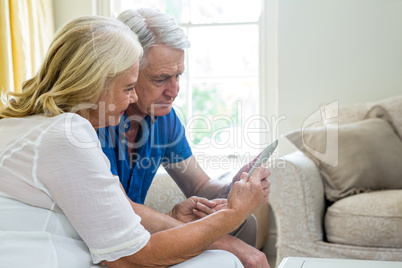 Senior couple using digital tablet while sitting at home