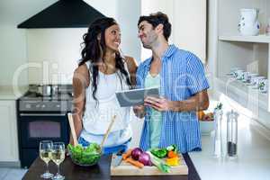 Young couple using digital tablet in kitchen