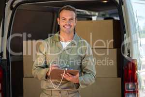 Happy delivery man writing on a clipboard