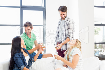 Smiling friends sitting on sofa drinking alcohol