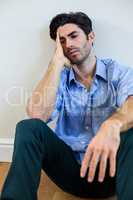 Depressed man with hand on forehead leaning against a wall