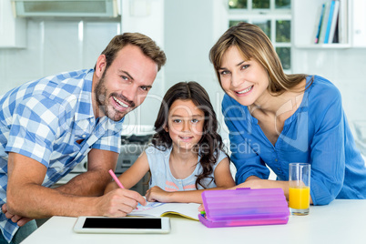 Happy father and mother assisting daughter in homework at home