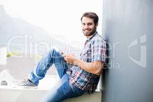 Man sitting on terrace holding digital tablet