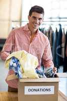 Young man sorting clothes from donation box