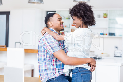 Young couple embracing face to face in kitchen