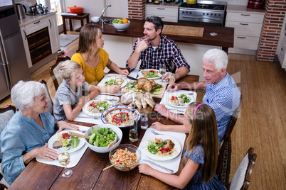 Multi-generation family talking while having meal in kitchen