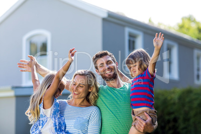 Happy parents carrying children with arms raised