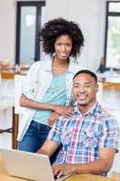 Portrait of young couple using laptop in kitchen