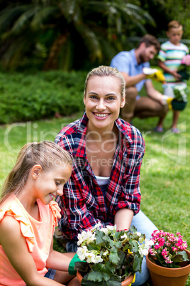 Mother helping daughter with flower pots in yard