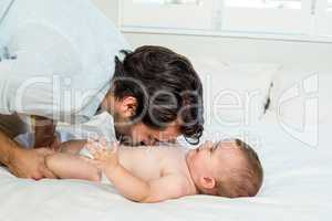 Playful father with cute baby boy on bed