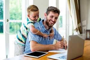 Happy father with son working by technologies at table