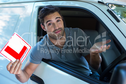 Handsome man shrugging while holding L plate