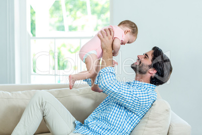 Father smiling while playing with son on sofa