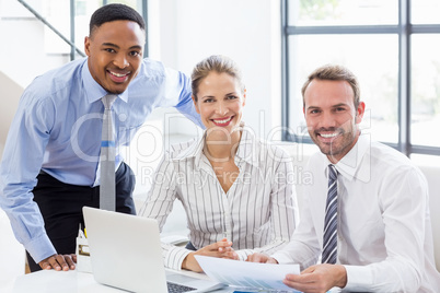 Portrait of happy business colleagues reviewing a report at desk
