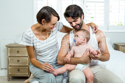 Parents sitting with son on bed at home