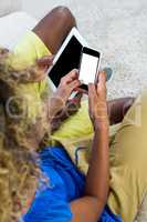 Couple using digital tablet and mobile phone in living room