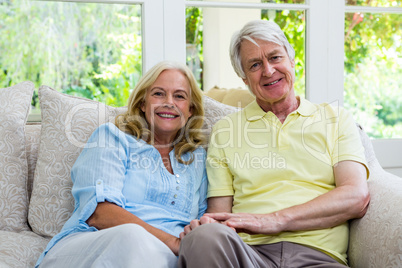 Smiling senior couple sitting on sofa at home