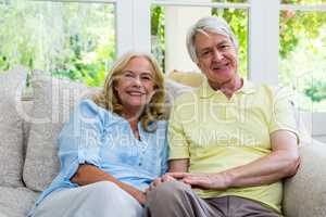 Smiling senior couple sitting on sofa at home