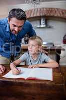 Father helping son with his homework in kitchen