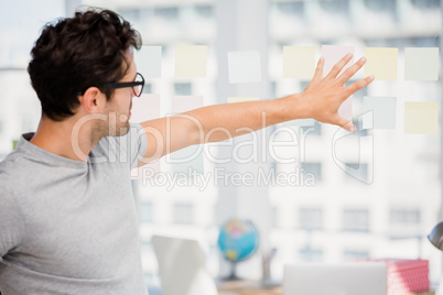 Thoughtful man looking at sticky notes on window