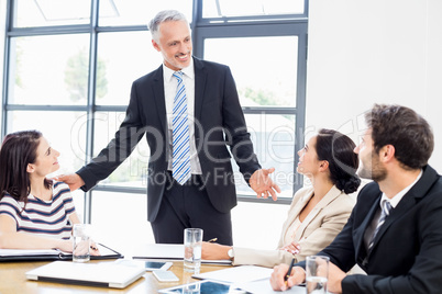 A businessman is talking to his colleagues and all are smiling